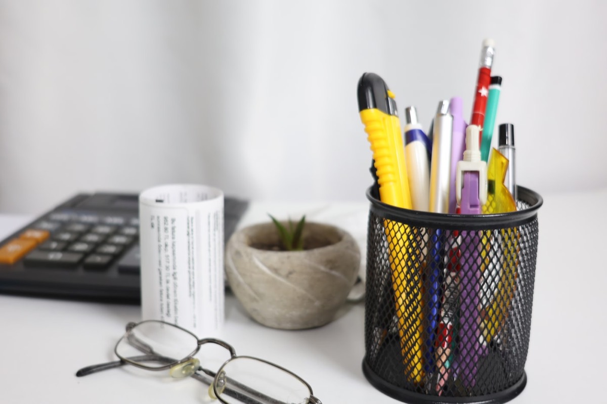 Desk with calculator, pens, and glasses