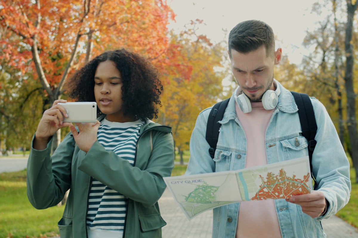 Couple looking at map and taking photo in park.