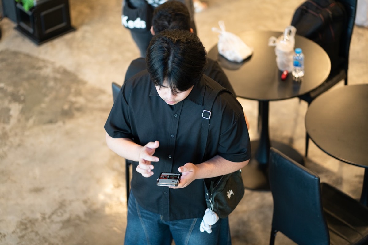 Man in black shirt using smartphone at cafe table