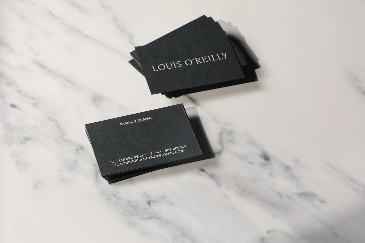 A pair of business cards sitting on top of a marble counter
